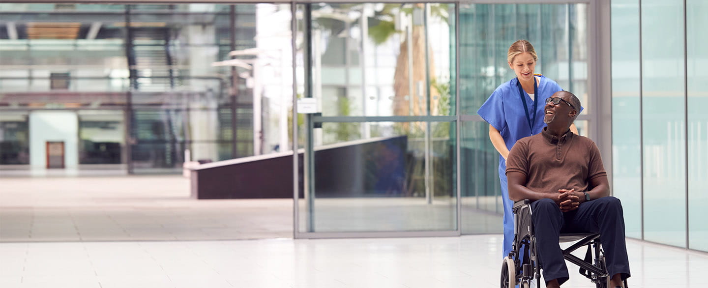 Nurse pushing patient in wheelchair.