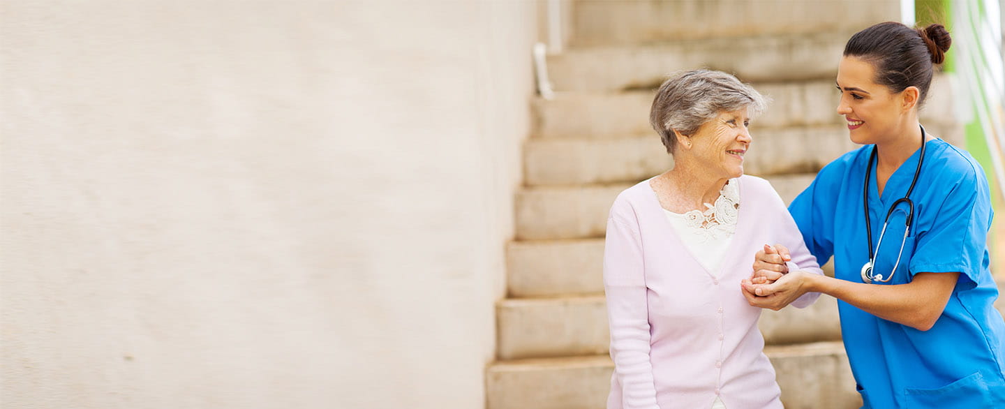 Nurse helping an older patient walk down stairs. 