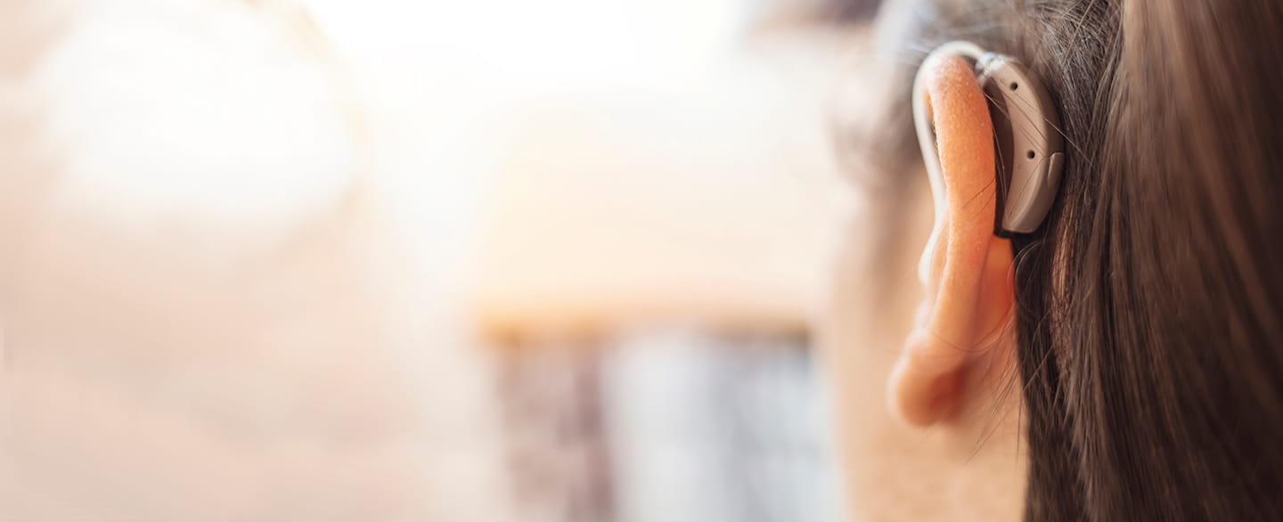 Up close photo of the back of a woman's ear wearing a hearing aid