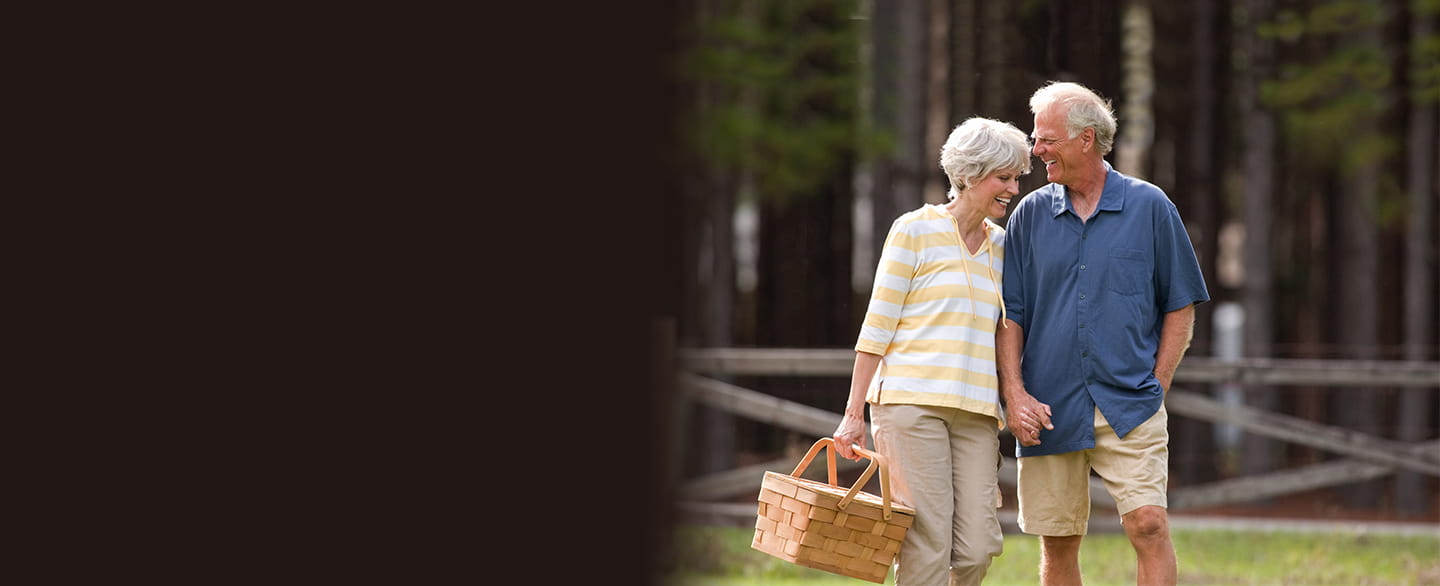 Retired couple walking in park.