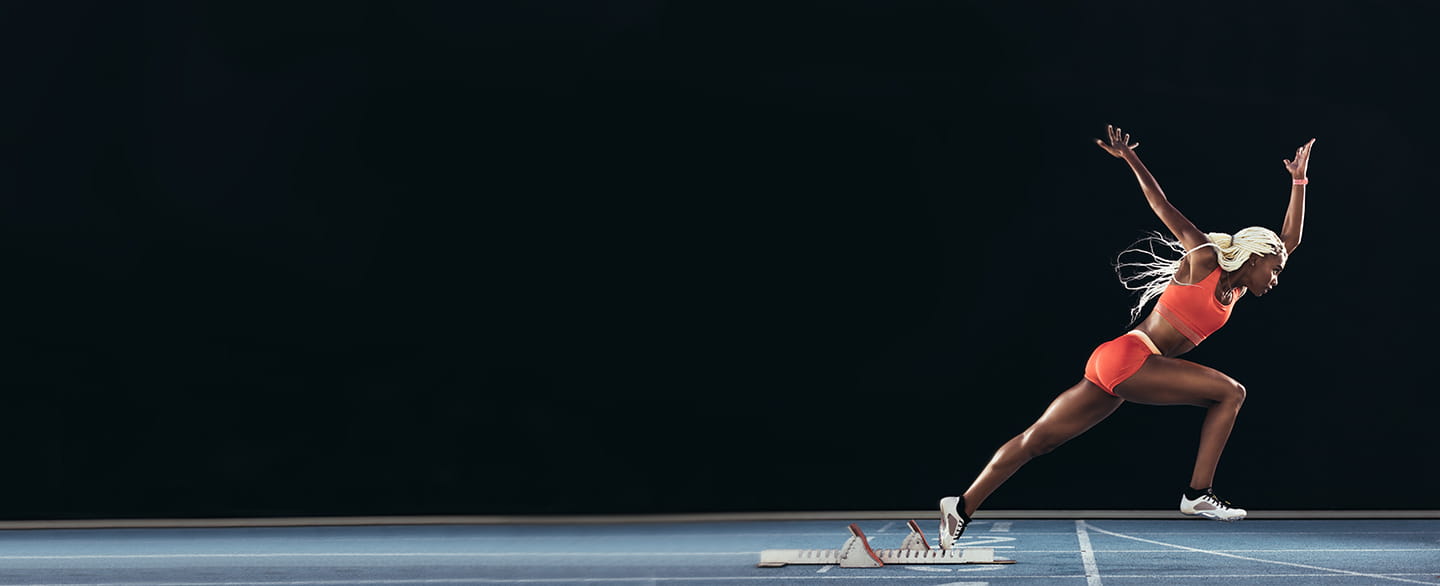 Woman taking off from starting block on a running track